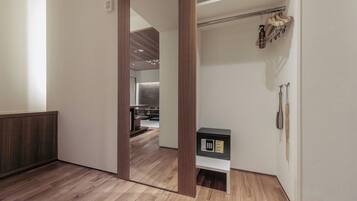 A modern interior with a wooden floor, a mirrored closet door, and a small black safe on a white shelf.