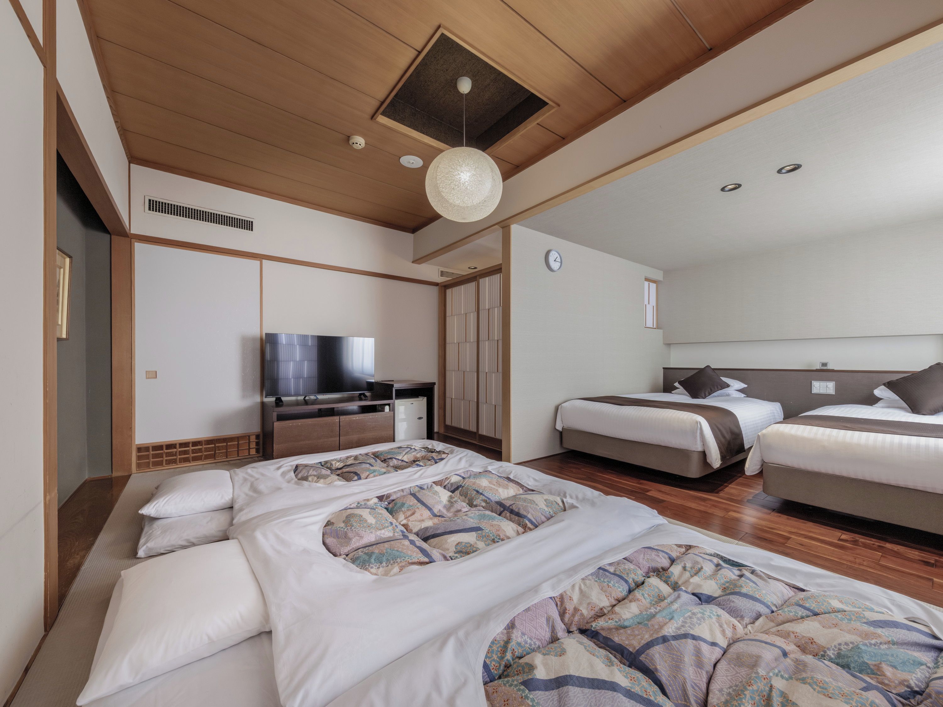 Habitación de hotel con una cama grande, televisor, armario y ventilador de techo.