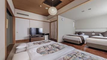 Habitación de hotel con una cama grande, televisor, armario y ventilador de techo.