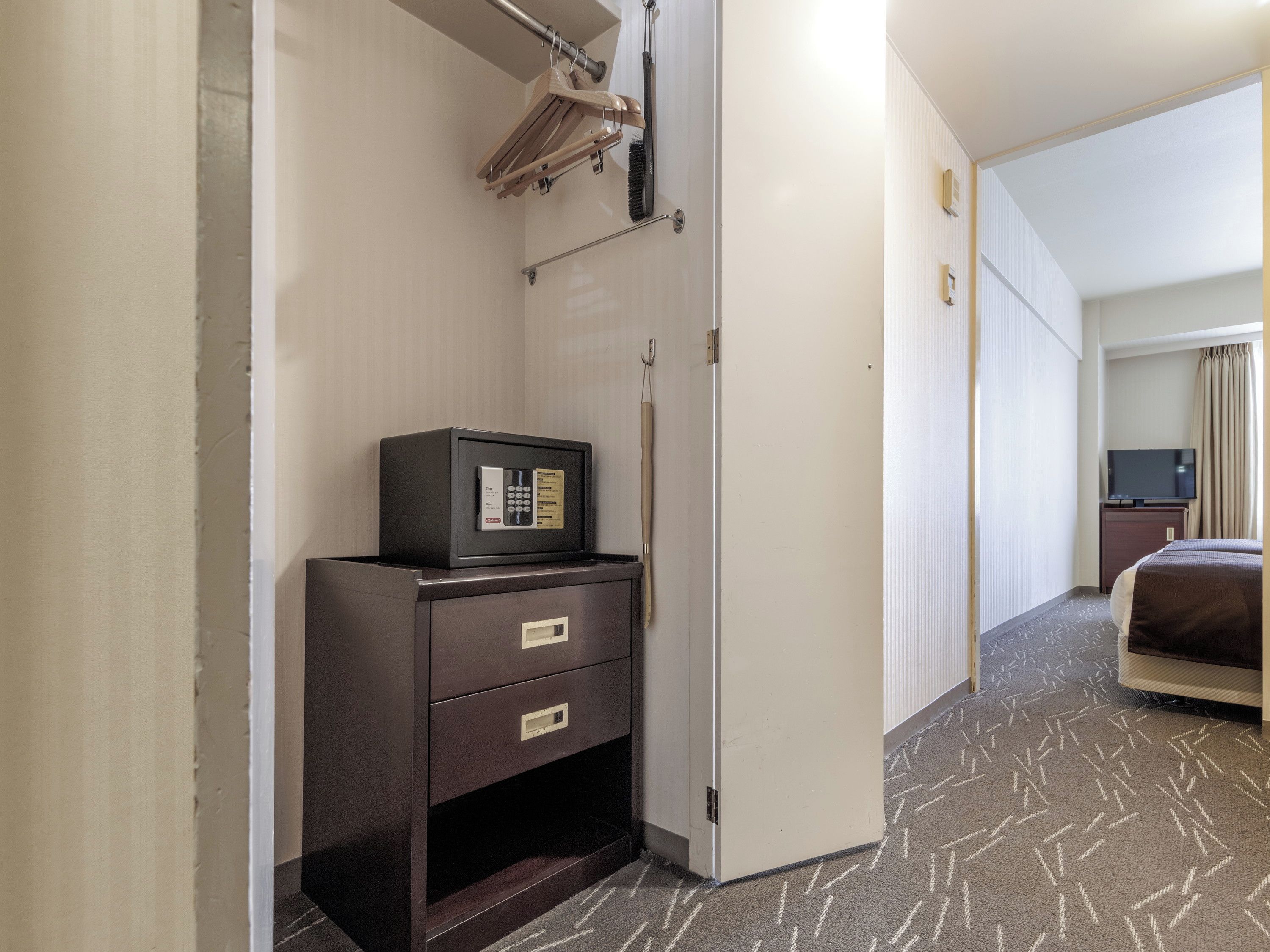 Habitación de hotel con minibar, televisión, cama y puerta que da a otra habitación.