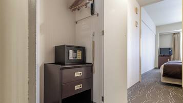 Habitación de hotel con minibar, televisión, cama y puerta que da a otra habitación.