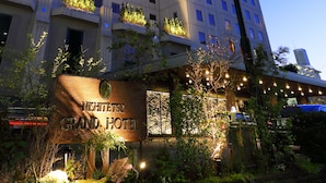 Un hotel rodeado de exuberante vegetación e iluminado con luces colgantes, con un letrero que dice "Nishiketo Grand Hotel".