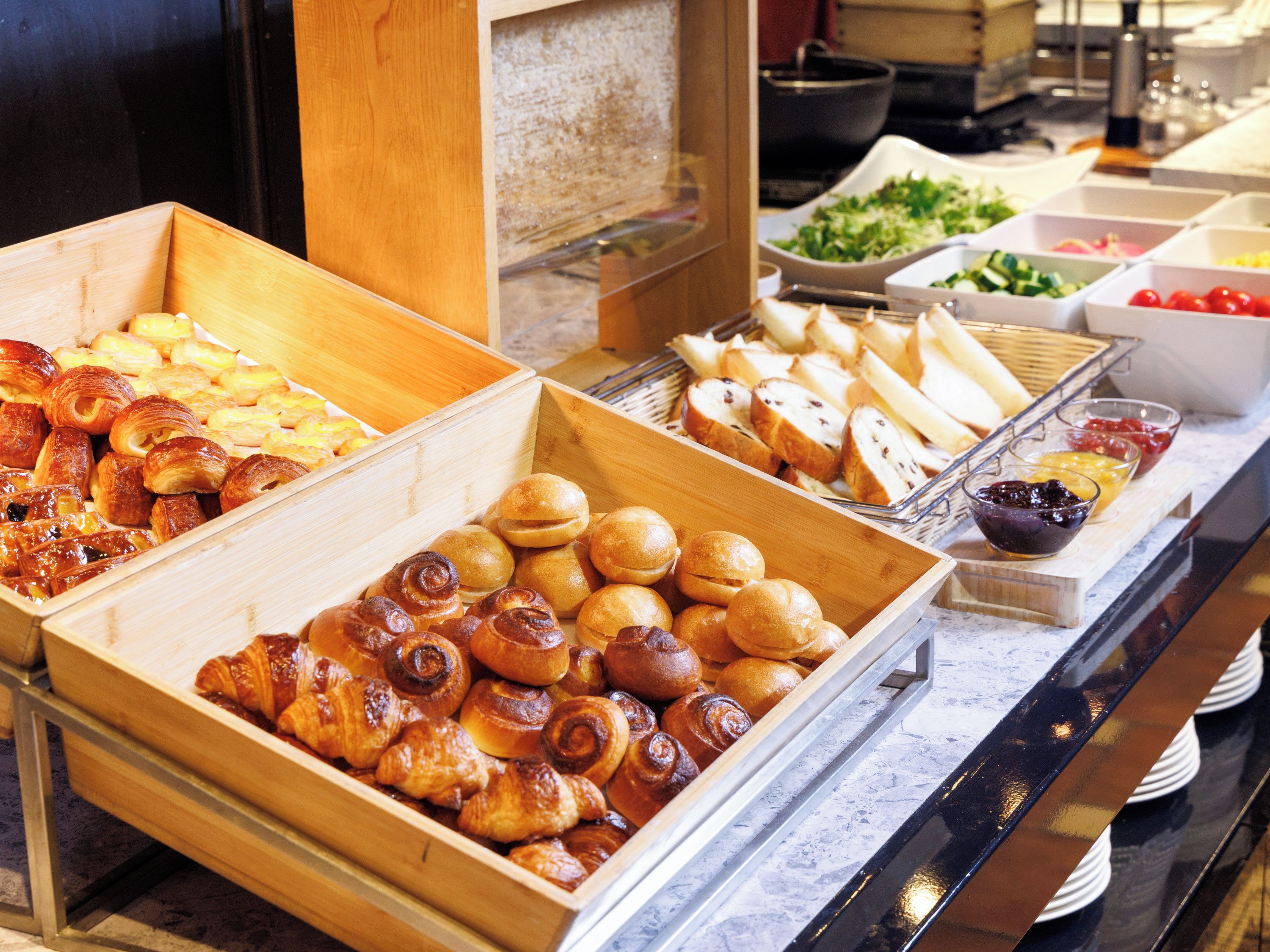 A buffet with various baked goods including pastries and bread.