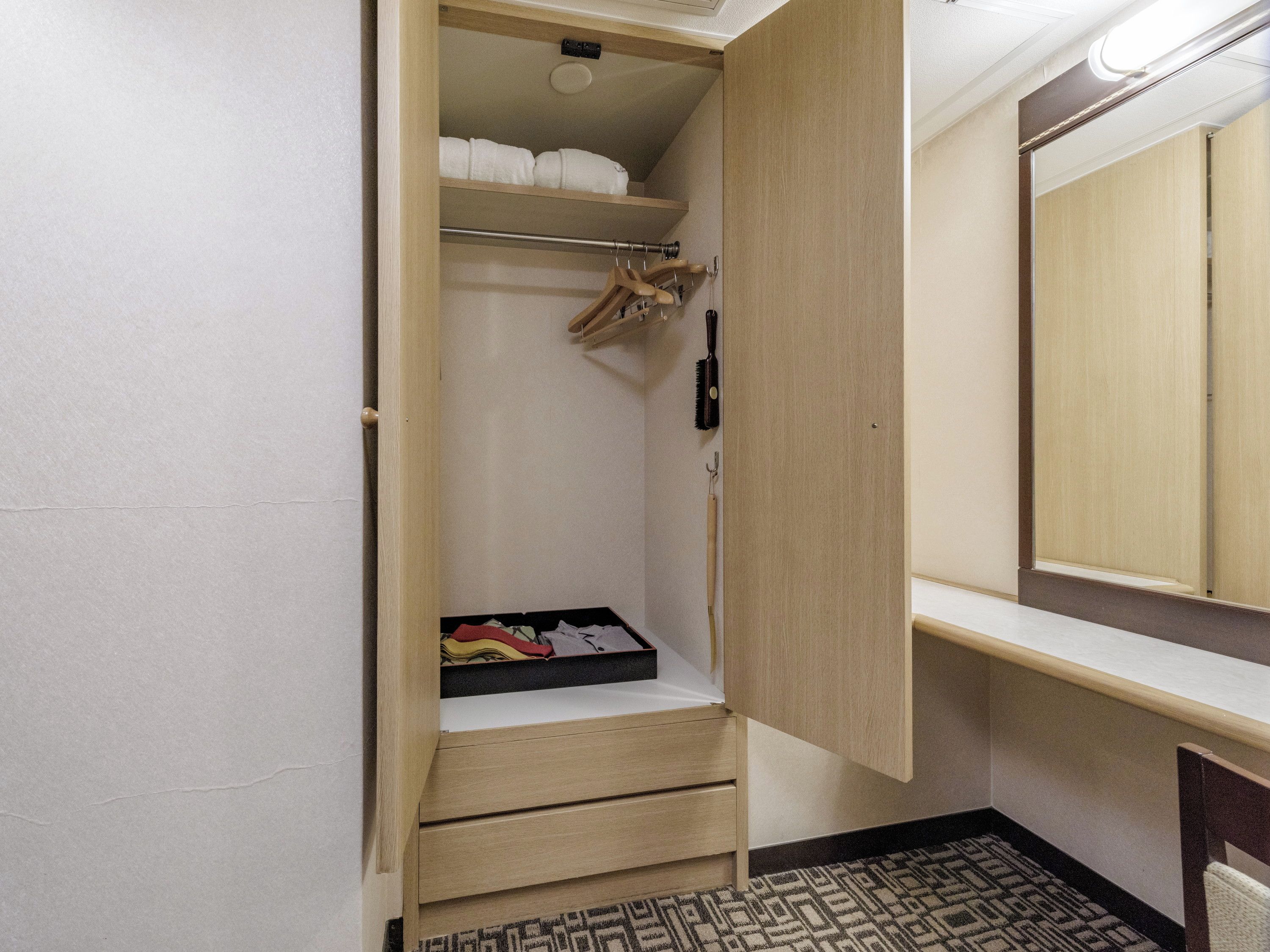A walk-in closet with hanging space, shelves, and drawers.