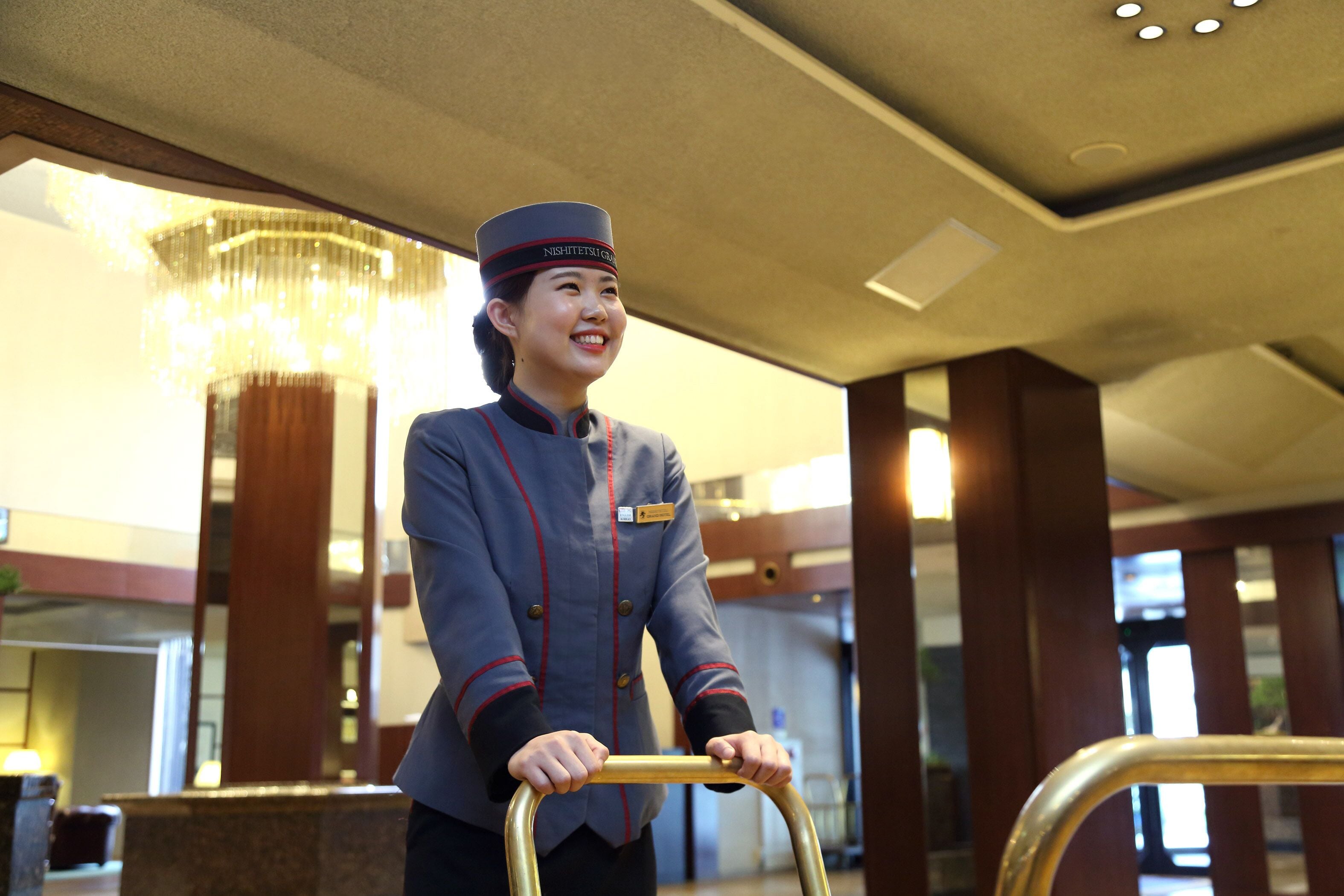 Ein Hotelmitarbeiter in Uniform schiebt einen Gepäckwagen.