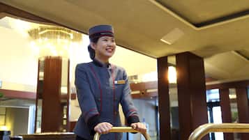A hotel staff member in uniform holding a luggage trolley.