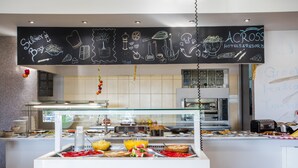 Zona de bufé con diversos alimentos y una pizarra con dibujos relacionados con la comida.