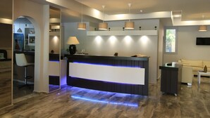 Un área de recepción moderna con mostrador, taburetes, iluminación colgante y televisor de pantalla plana.