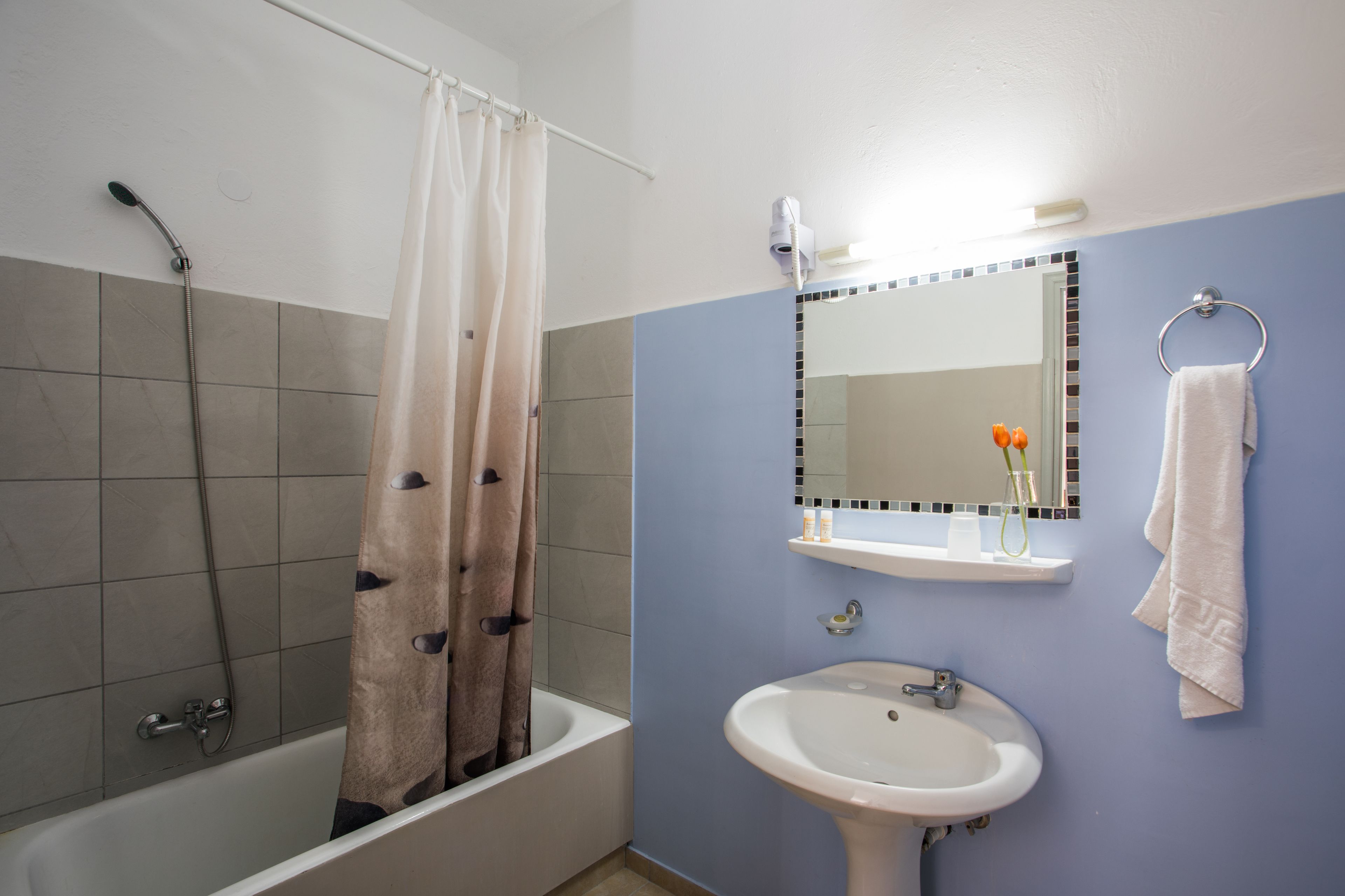 Een badkamer met een bad, wastafel, spiegel en handdoekhouder.