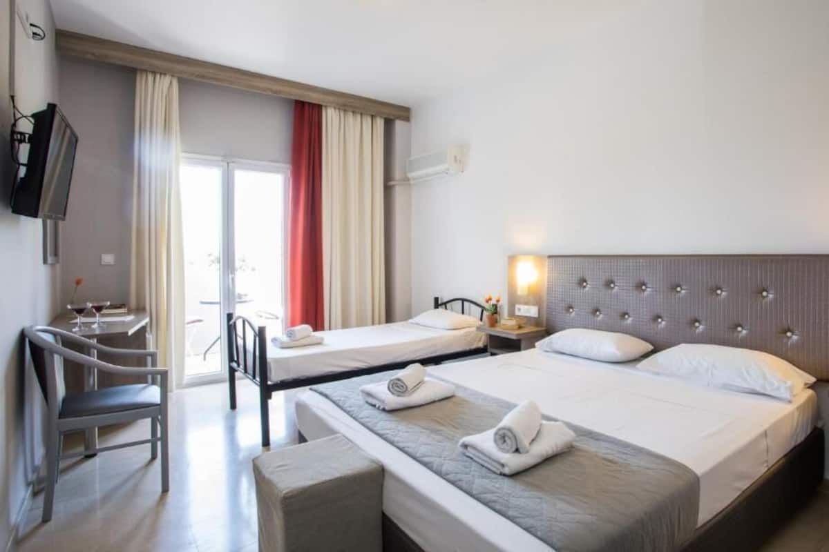 Una habitación de hotel con dos camas, un escritorio, una silla y un televisor.
