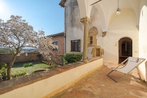 Relax in a serene courtyard surrounded by a beautifully maintained garden and a single lounge chair.