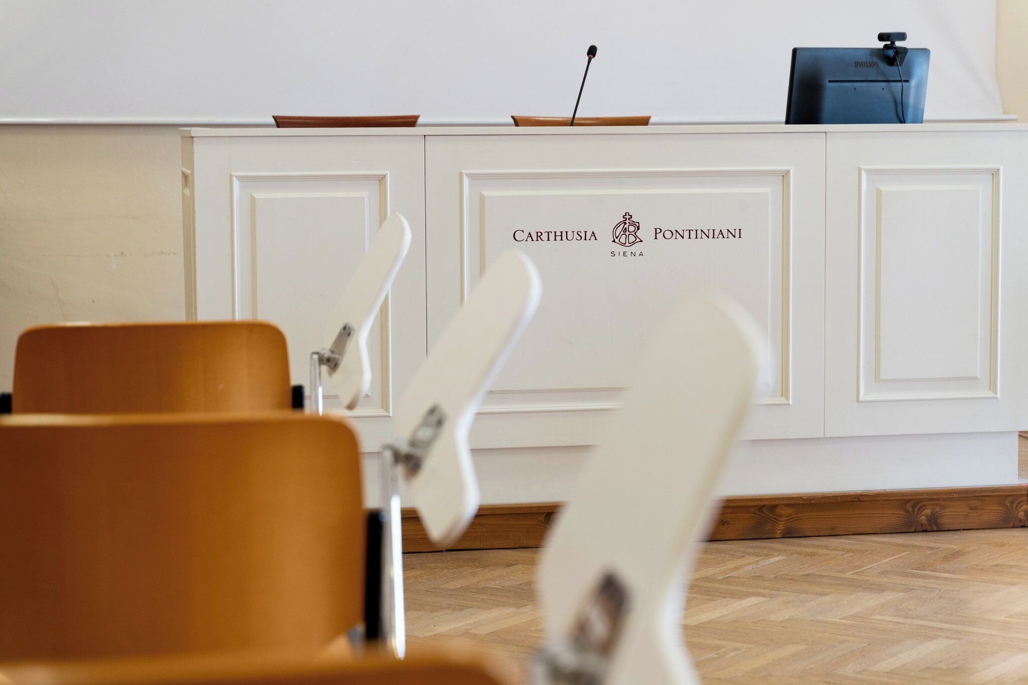 A reception desk with a white cabinet, two chairs in the foreground, and a blue bag on top.