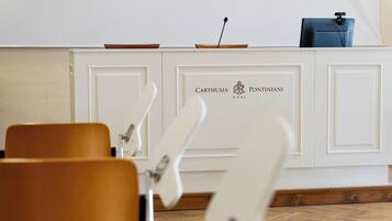 A reception desk with a white cabinet, two chairs in the foreground, and a blue bag on top.