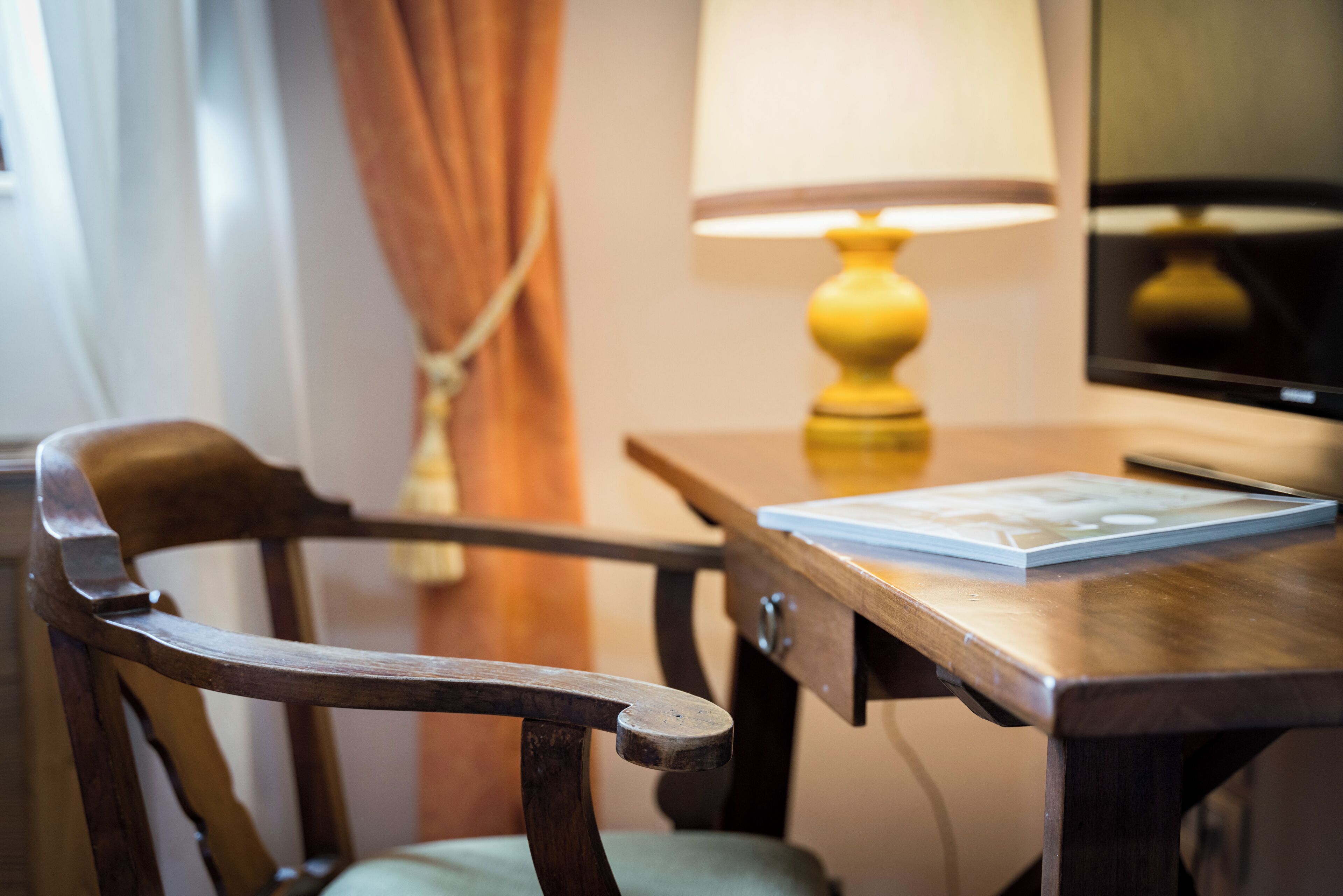 Een houten stoel, een tafel met een lamp en een boek.