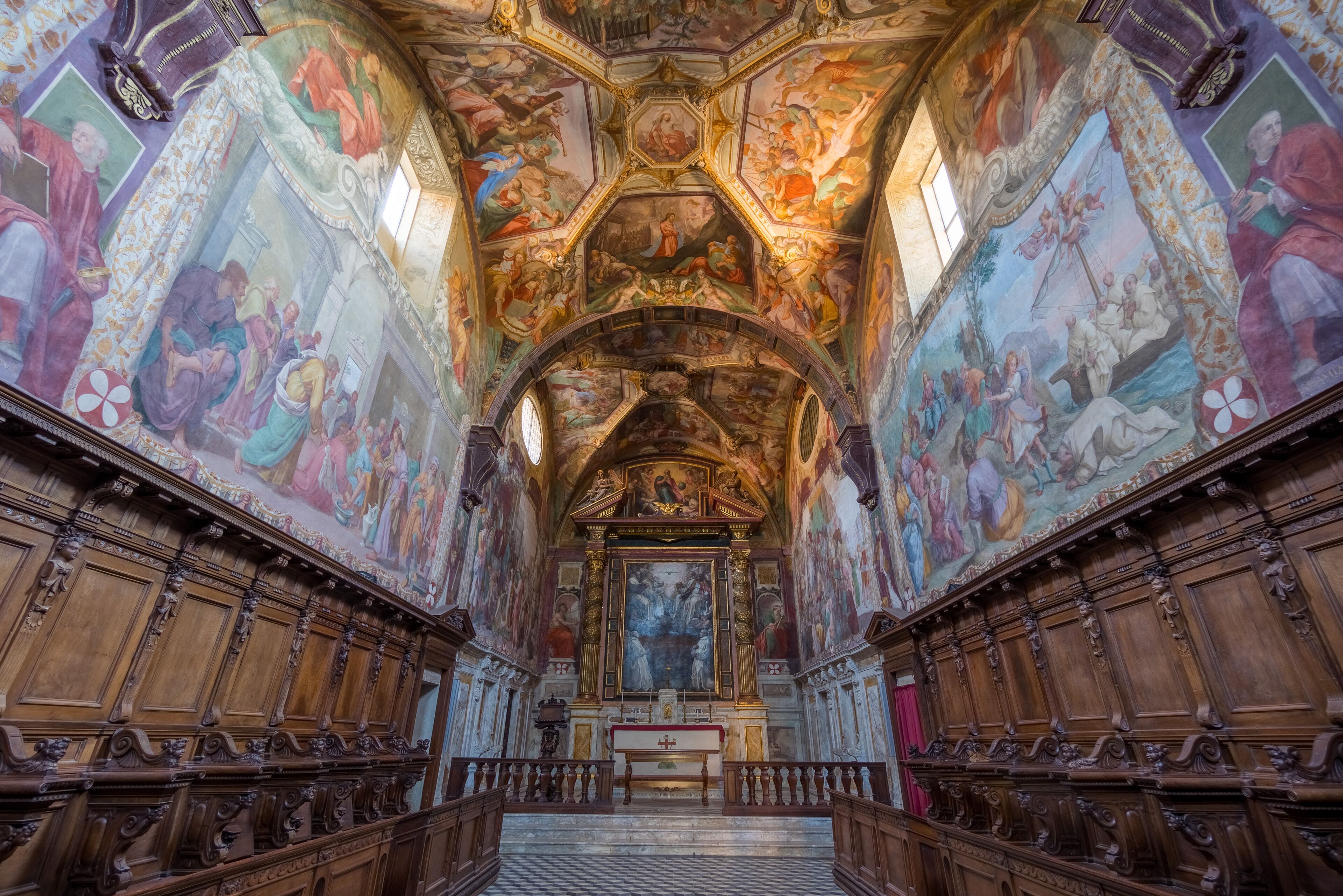 A grand hall with ornate wood paneling, a central altar, and detailed frescoes on the walls and ceiling.