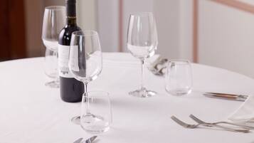 A table set with wine glasses, a bottle, and cutlery.