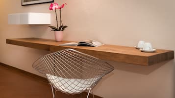 Un área de recepción moderna con un mostrador de madera, una silla de metal, una orquídea en maceta y una revista.