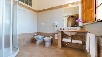 Een badkamer met douche, toilet, wastafel en bidet.