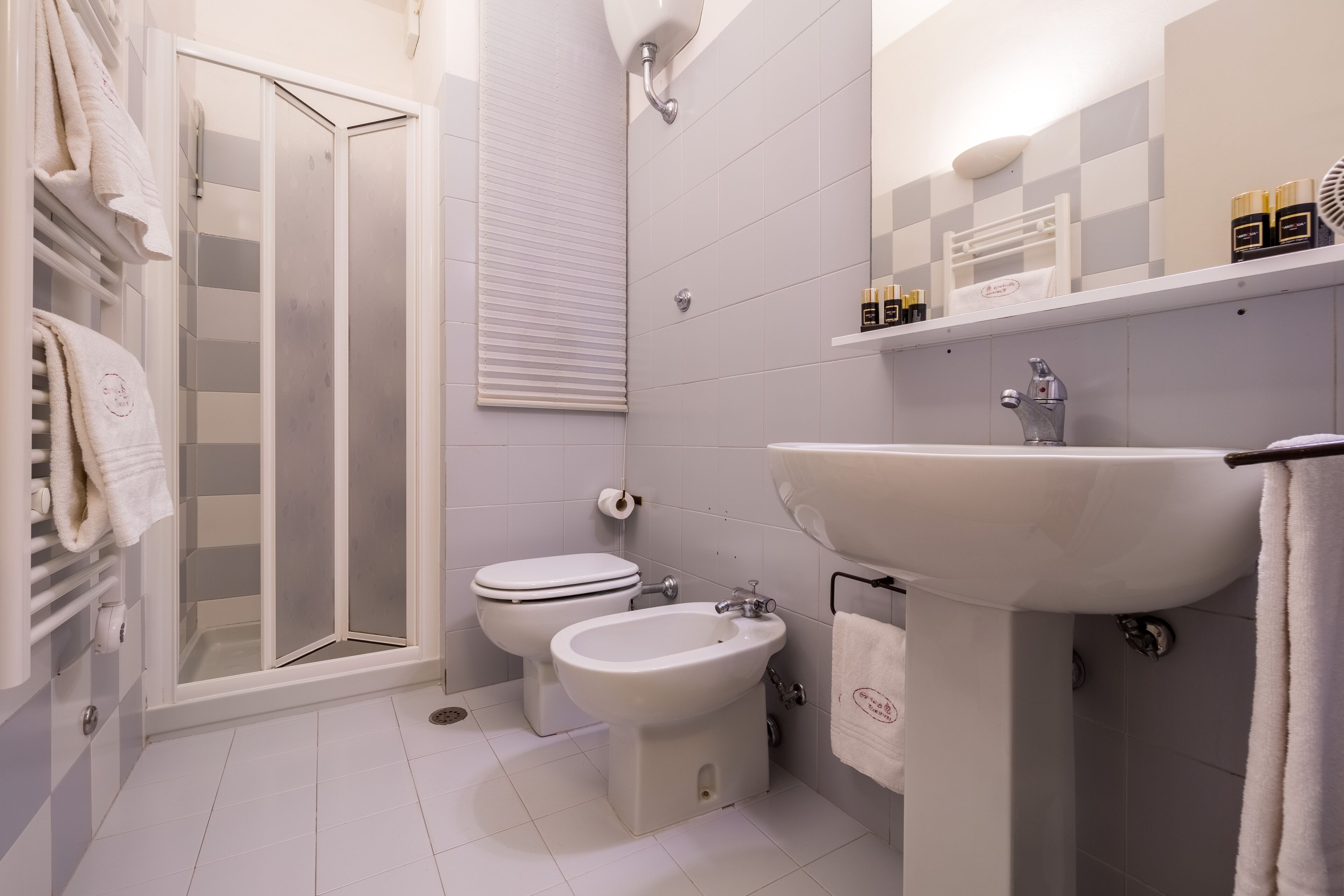 Un bagno moderno con box doccia in vetro, un water, un bidet e un lavandino.