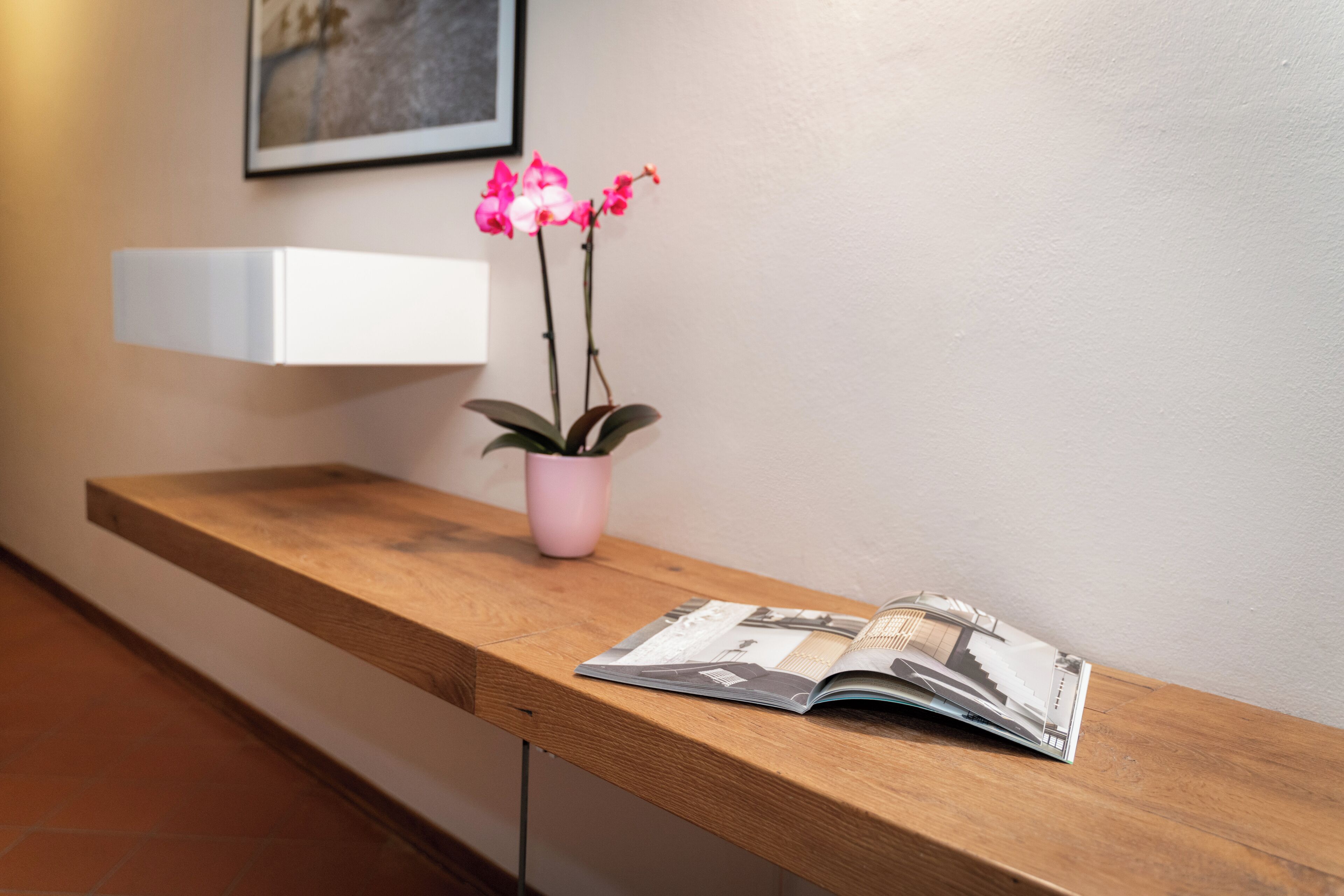 Un banc en bois, avec un pot de fleurs et un magazine ouvert.