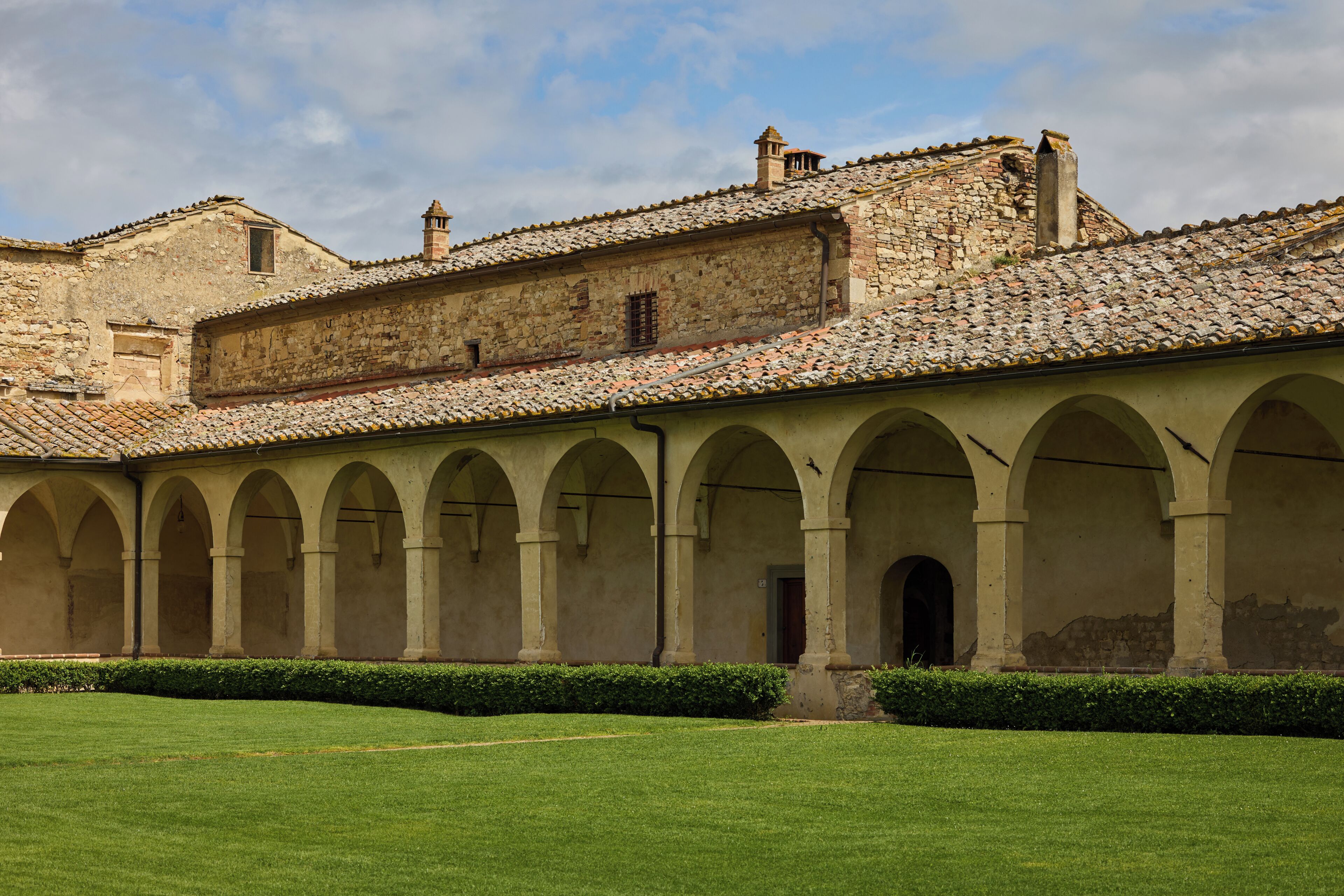 Un patio con una serie de arcos y un edificio con tejado de baldosas.