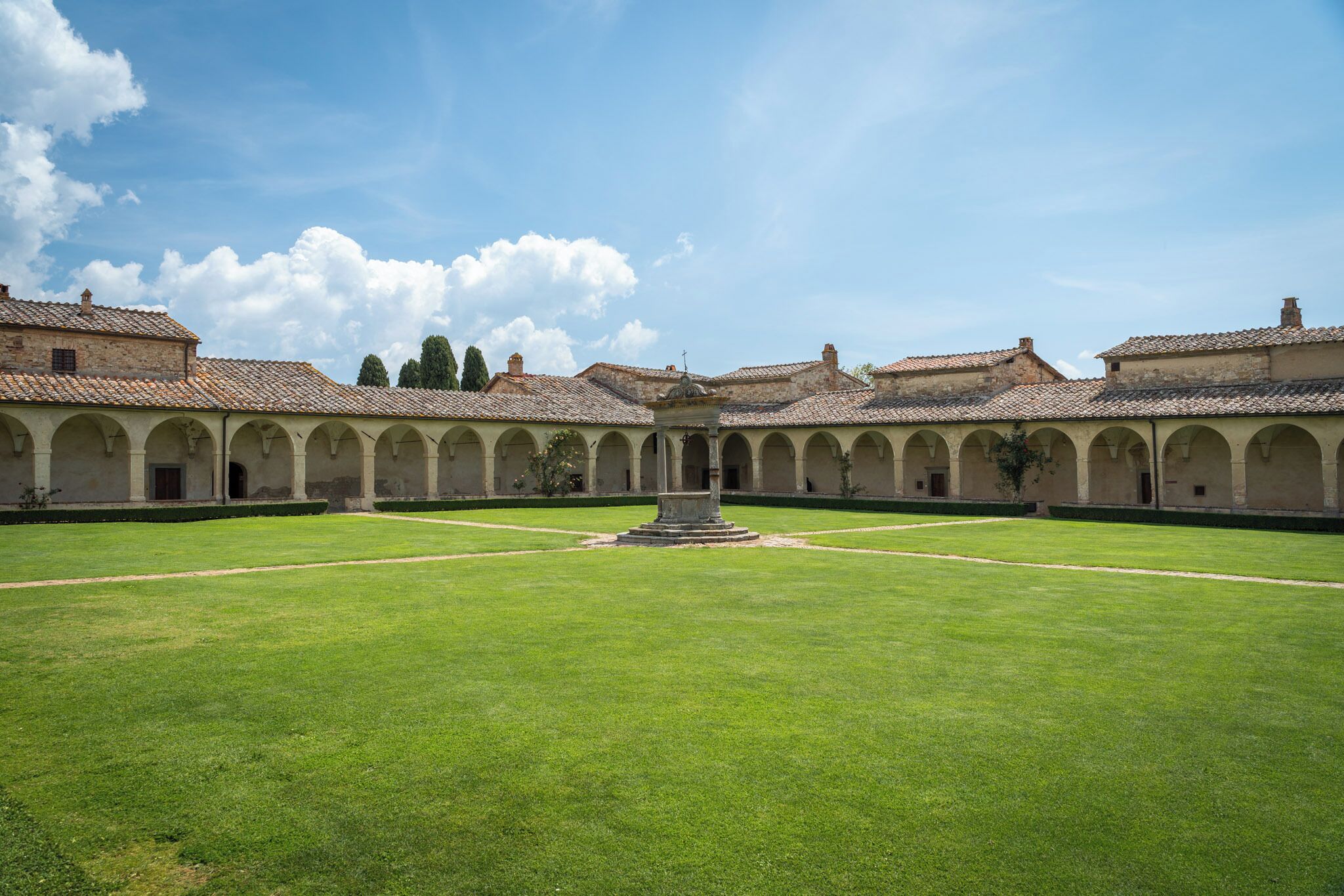 Un patio central con una fuente, rodeado de arcos y edificios con techos de tejas.