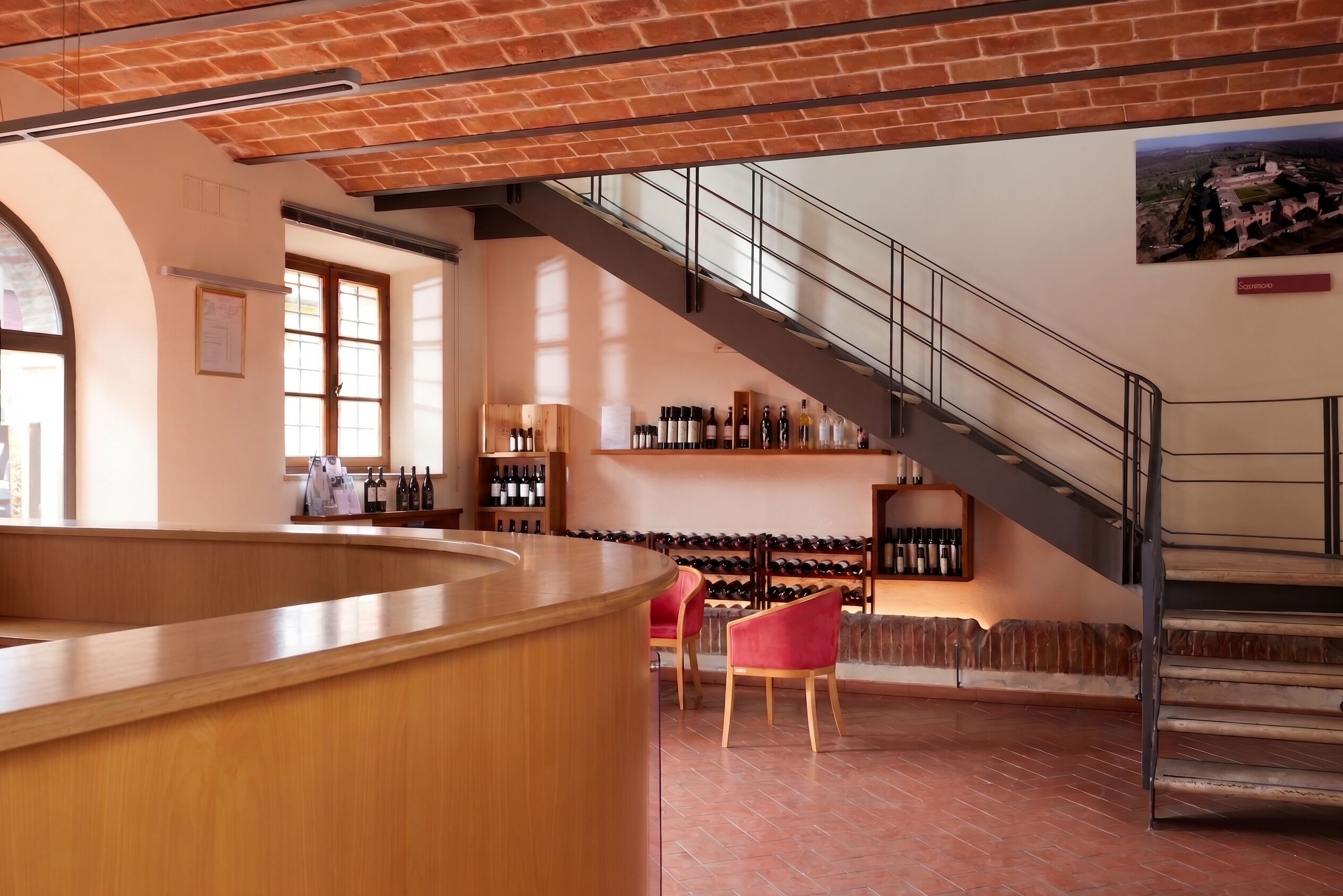 A bar area with a wooden counter, wine racks, and a staircase.