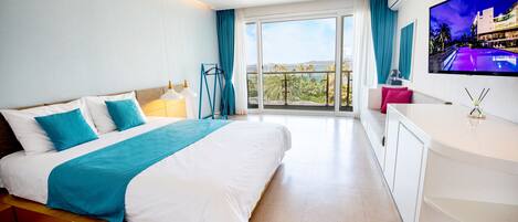 A modern hotel room with a large bed, a TV, and a balcony with a view.