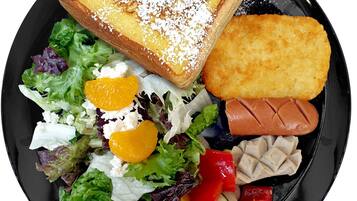 A plate with a variety of foods including a toasted sandwich, salad, and sliced vegetables.