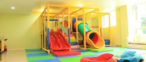 A play area with a slide, soft play mats, and a toy car.