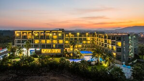 A modern hotel with multiple floors, a swimming pool, and a landscaped garden. - The Four Graces Resort (Seogwipo)