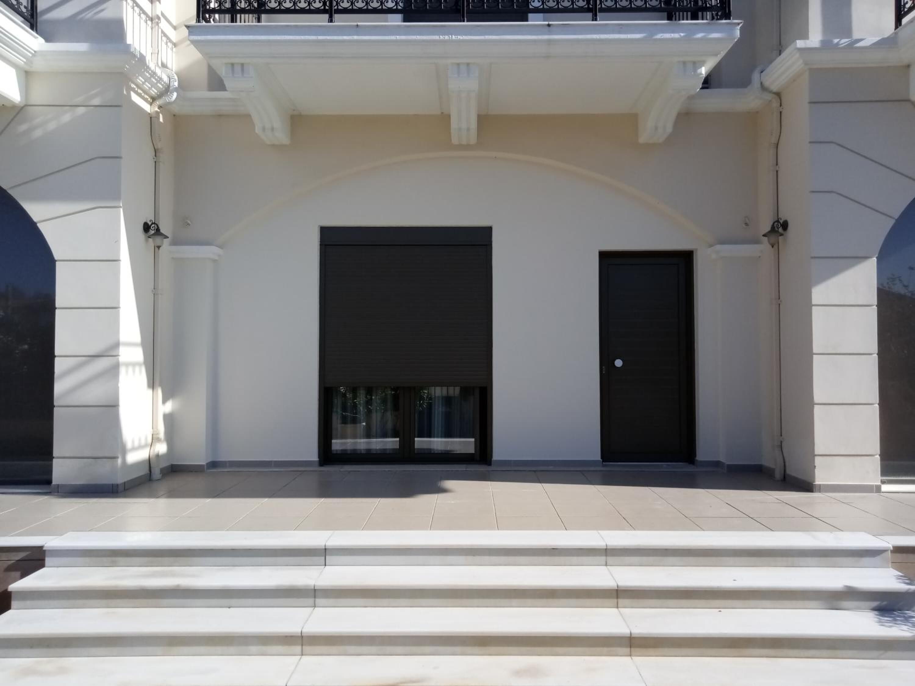 A building with a symmetrical facade, featuring two large black doors and a central arched entrance.