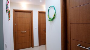 A hallway with wooden doors, a wall-mounted wreath, and a decorative floral arrangement. - Ilida Kourouta Studios (Ilida)