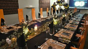A long dining table set for a formal event with candles, glassware, and a decorative centerpiece.