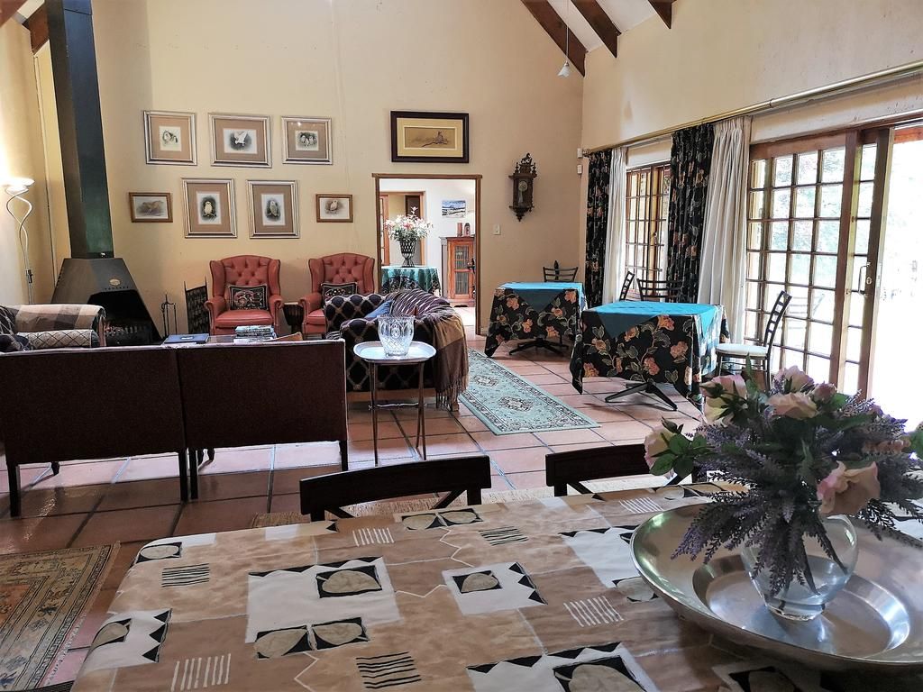 Un salon avec une cheminée, un coin repas avec une table et des chaises, et une vue par la fenêtre.