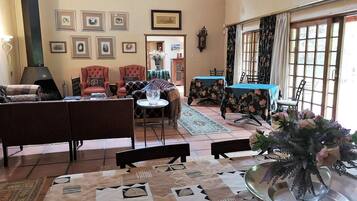 Un salon avec une cheminée, un coin repas avec une table et des chaises, et une vue par la fenêtre.