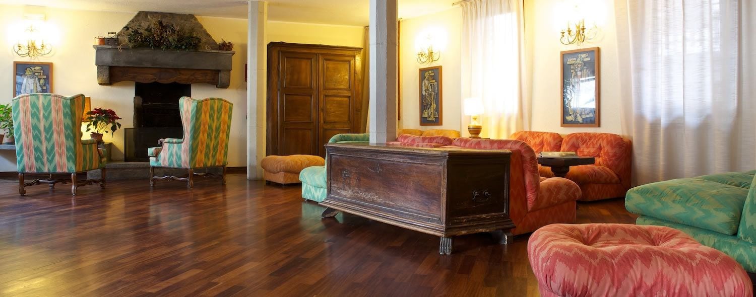 A spacious living room with a fireplace, wooden flooring, and colorful upholstered furniture.