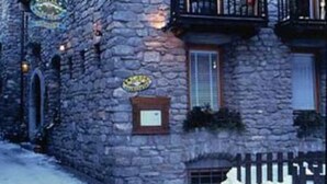 Un edificio de piedra con balcón, un cartel y una ventana.