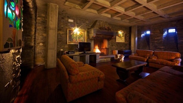 Un área de descanso acogedora con chimenea, asientos cómodos y una pared de piedra.