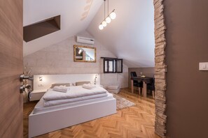 Une chambre moderne avec un plafond de style industriel, un grand lit, un bureau et un mur d’accent en pierre.