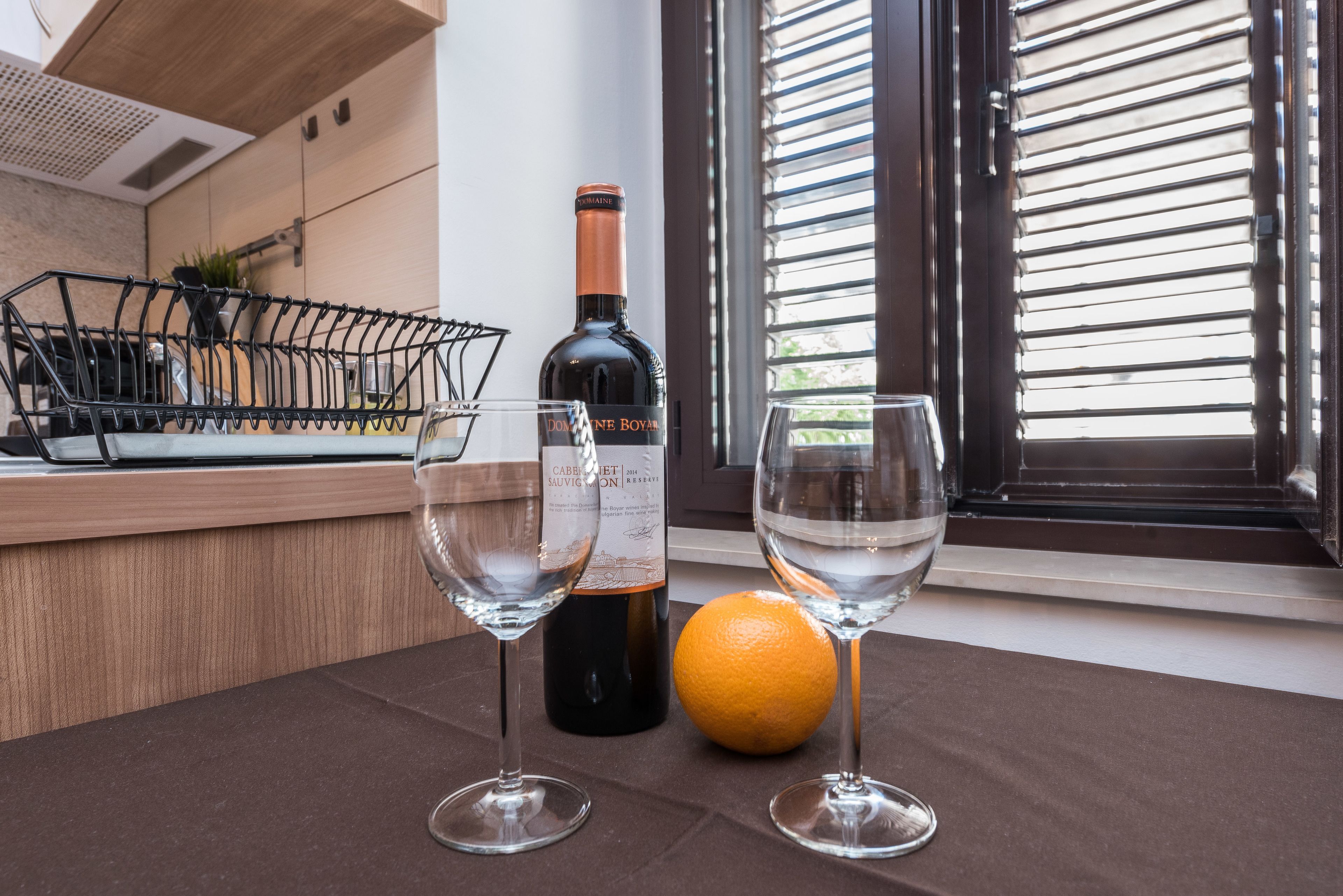 Un comptoir de cuisine avec deux verres à vin, une bouteille de vin et une orange.