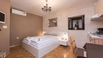A modern bedroom with a large bed, bedside tables, a small desk, and a window with blinds.
