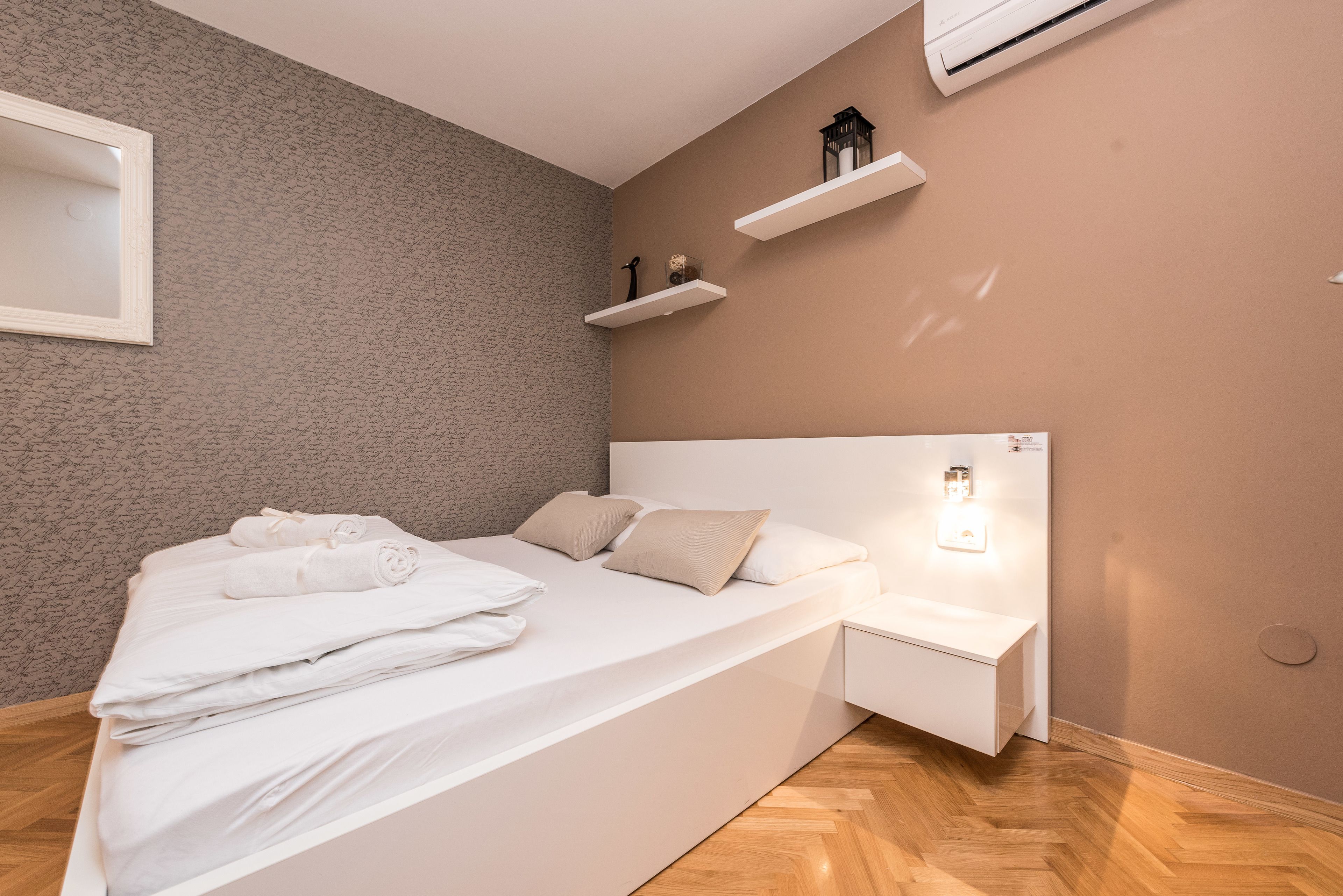 Une chambre à coucher moderne avec un lit, une table de chevet et des étagères murales.