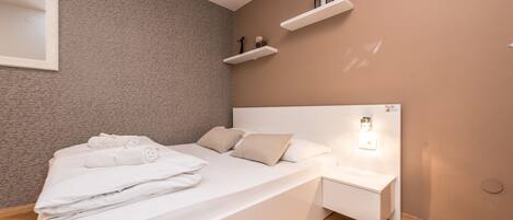 Ein modernes Schlafzimmer mit Bett, Nachttisch und Wandregalen.