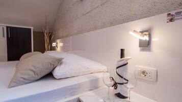 A modern bedroom with a bed, bedside table, and wall-mounted light fixture.