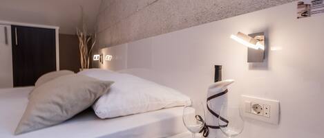Une chambre à coucher moderne avec un lit, une table de chevet et un luminaire fixé au mur.