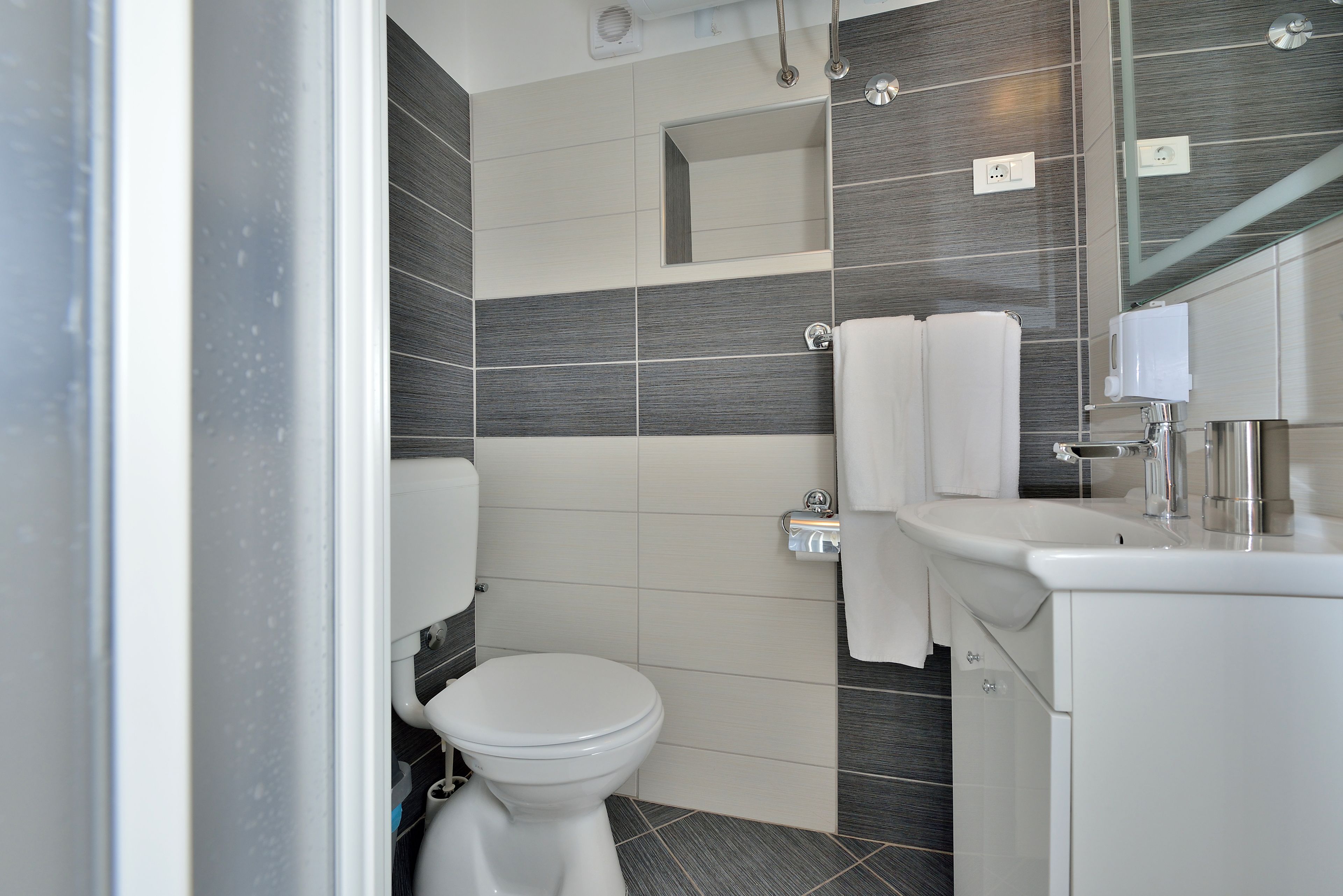 A modern bathroom with a toilet, sink, and mirror.