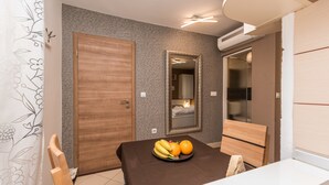 A dining area with a table set for two, a mirror above the table, and a wooden door in the background. - Apartments Donat Zadar (Zadar)