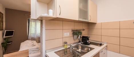A compact kitchen with a sink, countertop, and cabinets.
