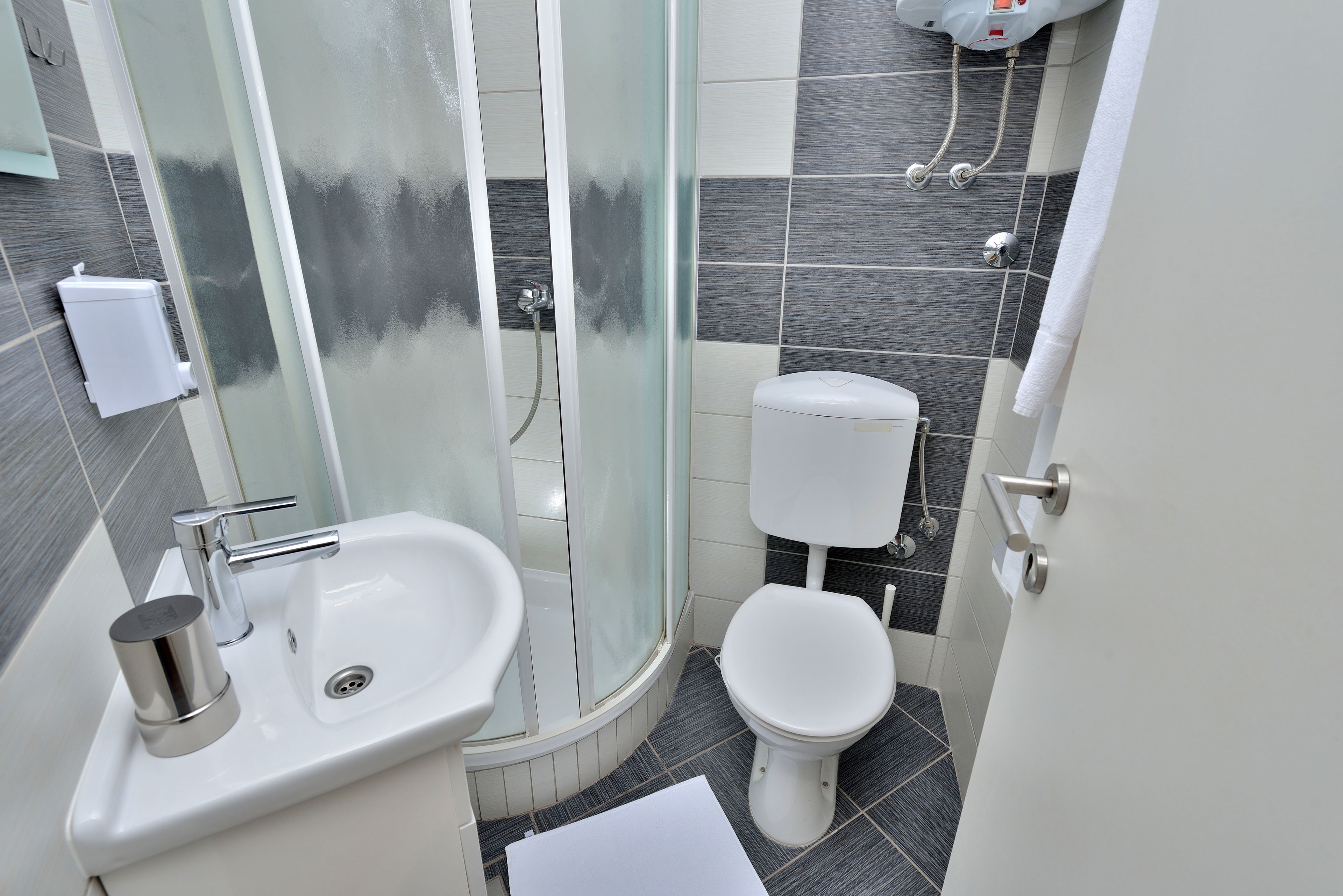 A modern bathroom with a glass shower enclosure, a white sink, and a toilet.